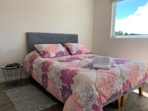 a bedroom with a bed with a pink blanket and a window at Departamento nuevo en exclusivo sector de Puerto Montt in Puerto Montt