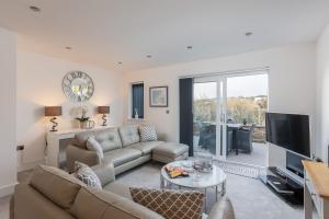 een woonkamer met een bank en een tv bij Rutland Heights,A Fantastic Modern Coastal House, Sea Views, Garden, Terraces, 2x Allocated Private Parking Spaces plus Free Private use of Electric Vehicle Point Meadfoot Beach only 5mins away! Also Shops, Bars and Restaurants just a 10 minute walk! in Torquay