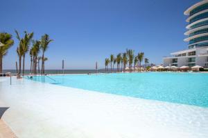 a large swimming pool with palm trees and a building at Estudio 573 Nuevo Vallarta, frente al mar, equipado y amueblado ! in Nuevo Vallarta  +55 photos