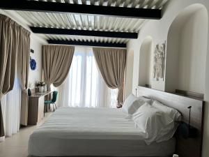 Un dormitorio con una gran cama blanca y una ventana en Boutique Hotel Palazzo Donna Iulia, en Pozzuoli