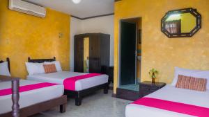 a hotel room with two beds and a mirror at Hotel Mucuy in Mérida