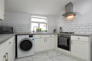 una cocina blanca con lavadora. en Fully Refurbed : DRIVEWAY : HotTub : Central Location en Portsmouth