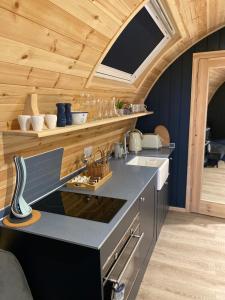 a kitchen in a tiny house with wooden ceilings at Craigend Farm Holiday Pods - The Curly Coo in Dumfries