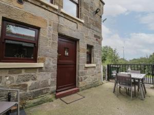 a stone building with a wooden door and a table and chairs at Foulsyke Farm Cottage in Saltburn-by-the-Sea