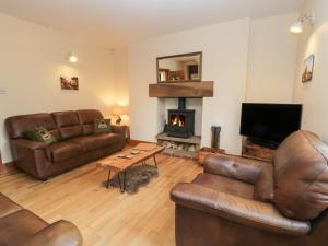 a living room with leather furniture and a fireplace at Foulsyke Farm Cottage in Saltburn-by-the-Sea