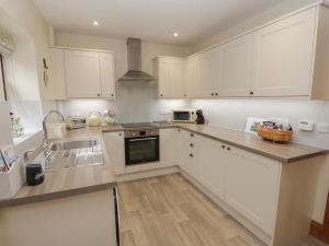a kitchen with white cabinets and a sink at Foulsyke Farm Cottage in Saltburn-by-the-Sea