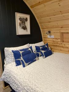 a bedroom with a bed with blue pillows on it at Craigend Farm Holiday Pods - The Curly Coo in Dumfries