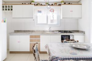 a white kitchen with a table and a sink at Lindo residencial no centro de Gramado in Gramado