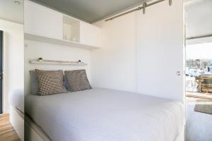 a bedroom with white walls and a bed with two pillows at The Homeboat Company Albufeira in Albufeira