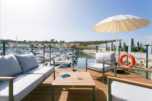 a patio with a couch and an umbrella and boats at The Homeboat Company Albufeira in Albufeira