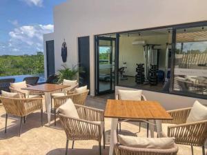 un patio con mesas, sillas y ventanas en BEAUTIFUL SUIT WITH INFINITY POOL AND GYM IN THE MIDDLE OF THE JUNGLe and grill, en Tulum