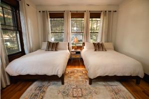two beds in a room with windows and a rug at Gulf Coast Craftsman - Cozy, Charming & Central! in Gulfport