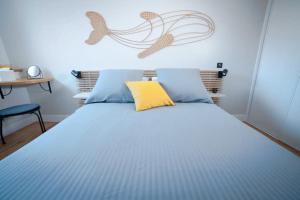 a bedroom with a blue bed with a yellow pillow at Coup de Cœur assuré pour ce T2 rénové Hyper centre in Biarritz