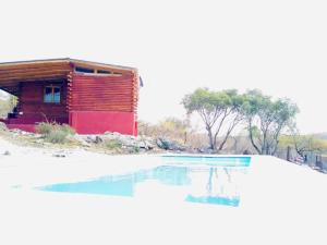 a house with a swimming pool in front of it at Cabañas Achalay in Valle Hermoso