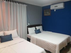 Duas camas num quarto com paredes azuis em Casa 1 Encanto dos Mares em Itapema