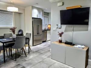 a kitchen and dining room with a table and a television at New Urban Modern Main St. Coach House in Vancouver