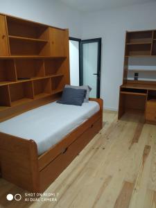 a bedroom with a bed with wooden shelves and a desk at Wood Steel & Glass in Marinha Grande