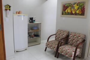 ein Wohnzimmer mit 2 Stühlen und einem Kühlschrank in der Unterkunft apartamento fruto da terra 302 VISTA LATERAL MONTANHAS in Caparaó Velho
