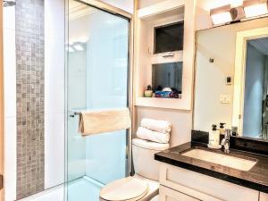 a bathroom with a toilet and a glass shower at New Urban Modern Main St. Coach House in Vancouver