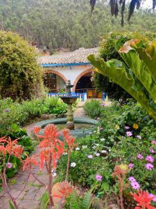 een tuin met een fontein en bloemen voor een gebouw bij Finca San Pedro in Sogamoso