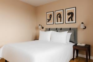 ロンドンにあるサコ フィッツロビアの白いベッド1台、壁に2枚の写真が飾られたベッドルーム1室