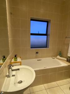 a bathroom with a tub and a sink and a window at Waves Edge CP3 in Cape Town