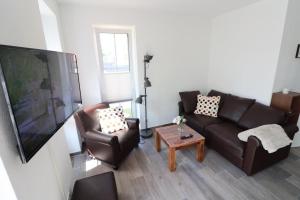 een woonkamer met 2 banken en een flatscreen-tv bij Ferienhaus-im-Angerdorf in Cuxhaven