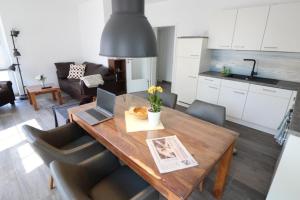 eine Küche und ein Esszimmer mit einem Holztisch und einem Laptop in der Unterkunft Ferienhaus im Angerdorf in Cuxhaven