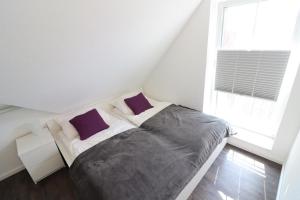 1 dormitorio con 1 cama con 2 almohadas moradas en Ferienhaus-im-Angerdorf, en Cuxhaven