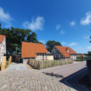 eine Reihe von Häusern mit orangefarbenen Dächern auf einer Straße in der Unterkunft Ferienhaus im Angerdorf in Cuxhaven