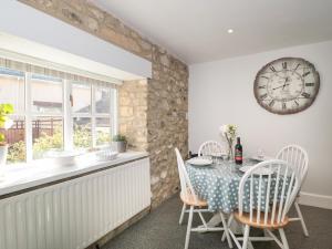 a dining room with a table and a clock on the wall at The Linhay in Axminster