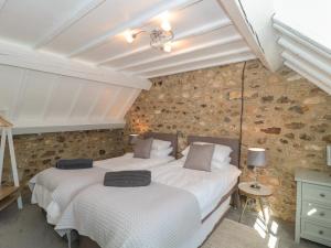 two beds in a room with a stone wall at The Linhay in Axminster