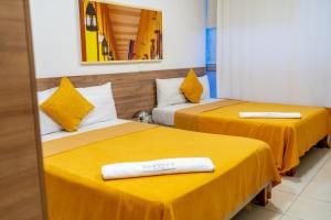two beds in a room with yellow sheets at Condina Hotel in Pereira