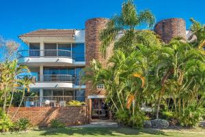 a large brick building with palm trees in front of it at Surf Haven opposite Clarkes Beach pool walk to CBD in Byron Bay