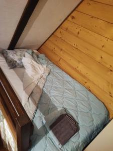 a bed in a room with a wooden wall at Ovcar banja in Čačak