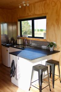 cocina con fregadero y encimera con 2 taburetes en Luxury Container Cabin, en Masterton