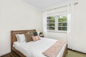 Dormitorio blanco con cama y ventana en Katoomba Getaway 3 Bedroom Villa en Katoomba