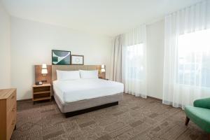 聖貝納迪諾的住宿－Staybridge Suites - San Bernardino - Loma Linda，卧室配有床、椅子和窗户。