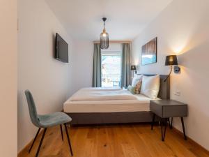 um quarto com uma cama, uma cadeira e uma janela em Ski Nature Apartment Lungau Top 13 em Mauterndorf