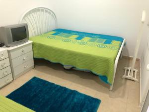 1 dormitorio pequeño con 1 cama y TV en Recanto do Sol, en Hortas