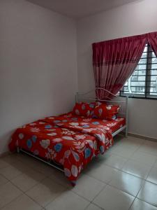 una camera da letto con un letto con un piumone rosso e una finestra di Homestay UmahMak a Bandar Puncak Alam