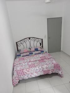 um quarto com uma cama com uma colcha rosa em Homestay UmahMak em Bandar Puncak Alam