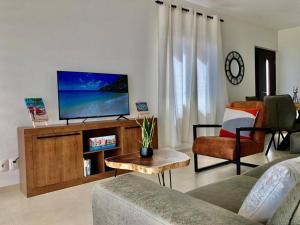 a living room with a tv and a couch and a table at The beach House- 1Room Apartment at Blue Bay resort in Sint Michiel