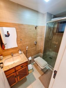 uma casa de banho com um chuveiro, um lavatório e um WC. em Apartamento pé na areia - Praia do Forte em Cabo Frio
