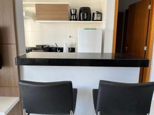 een keuken met twee zwarte stoelen en een aanrecht bij Flat 501 - Condominio Veredas do Rio Quente - Diferenciado com ar na sala e no quarto in Rio Quente
