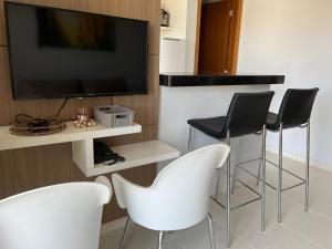 een woonkamer met witte stoelen en een flatscreen-tv bij Flat 501 - Condominio Veredas do Rio Quente - Diferenciado com ar na sala e no quarto in Rio Quente