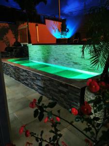 einen Pool mit grüner Beleuchtung an einer Backsteinwand in der Unterkunft Résidence B&L Lagon : Bungalow Atoll in Sainte-Luce