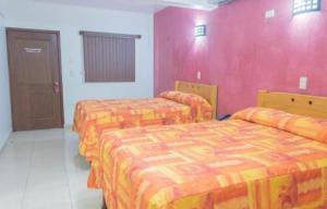 奧夫雷貢城的住宿－HOTEL DEL CENTRO，配有粉红色墙壁的客房内的两张床