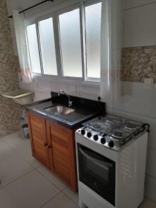 a small kitchen with a stove and a sink at Canto Verde Aptos II in Caraguatatuba
