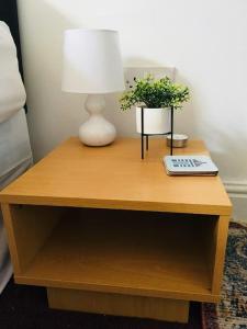 a wooden table with a lamp and plants on it at Hillcrest Cottage, comfy flat, trendy Uplands area in Swansea